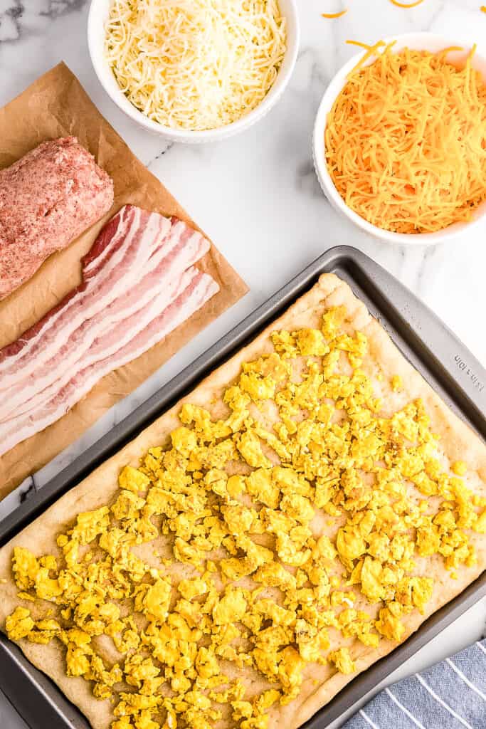 Overhead image of pizza dough with scrambled eggs on top