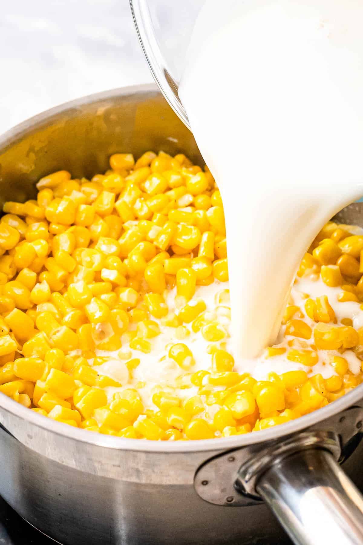 Milk being poured into a saucepan with corn