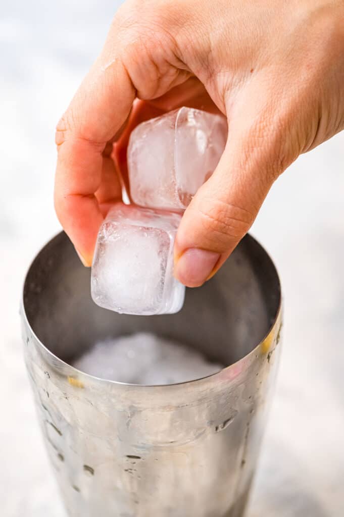 Placing ice cubes into cocktail shaker