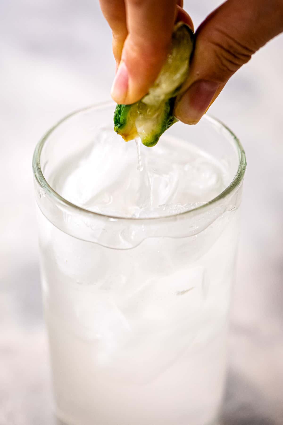 Hand squeezing lime into cocktail