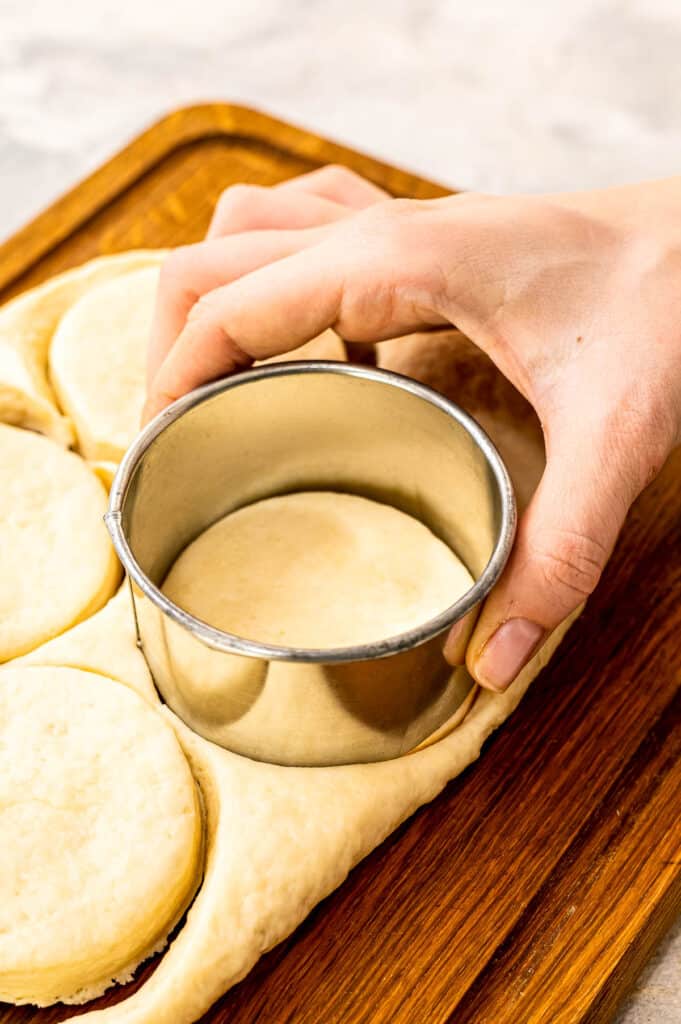 Using a biscuit cutter to cut out biscuit from dough