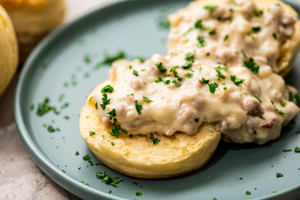 Biscuits split open and topped with sausage gravy on plate