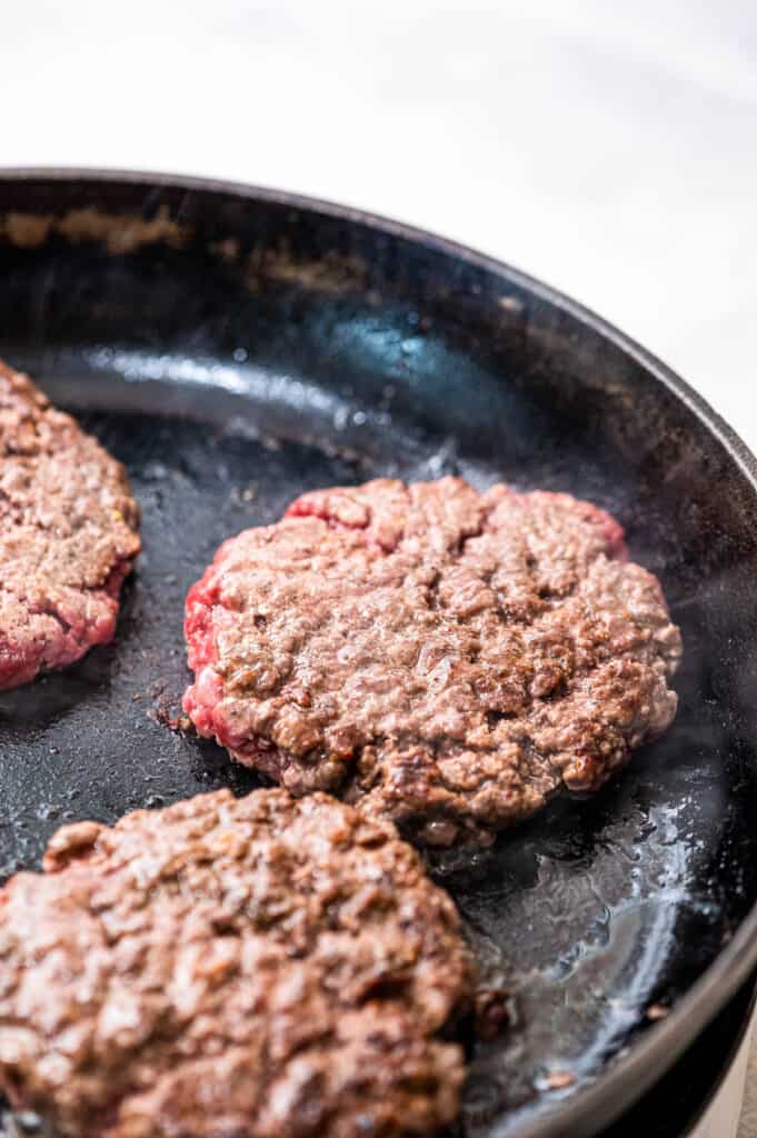 Hamburger patties cooking in skillet