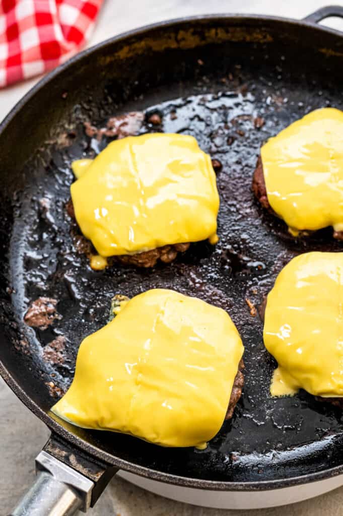 Hamburger patties with cheese slices in skillet