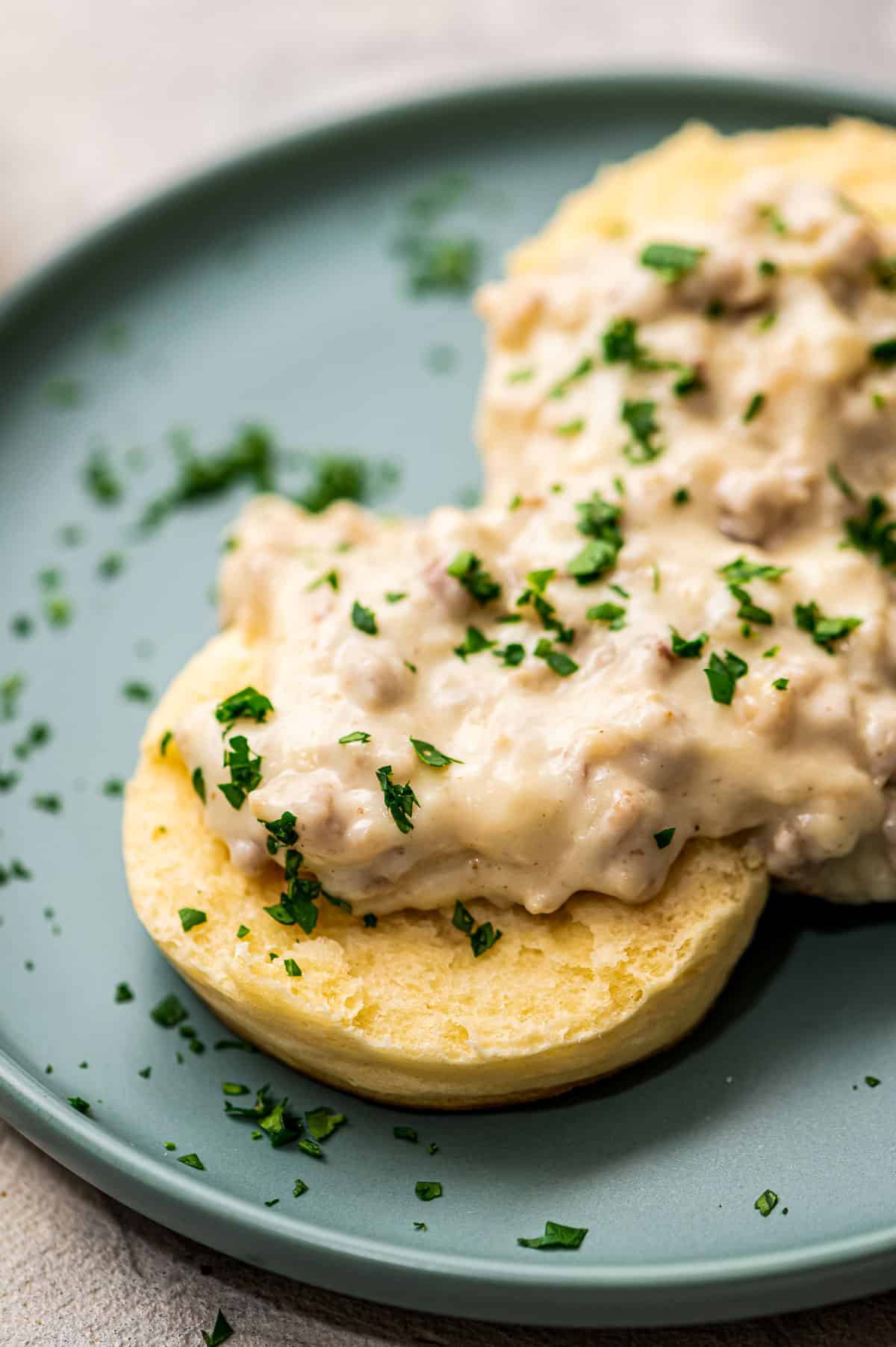 Split open biscuit topped with sausage gravy on plate