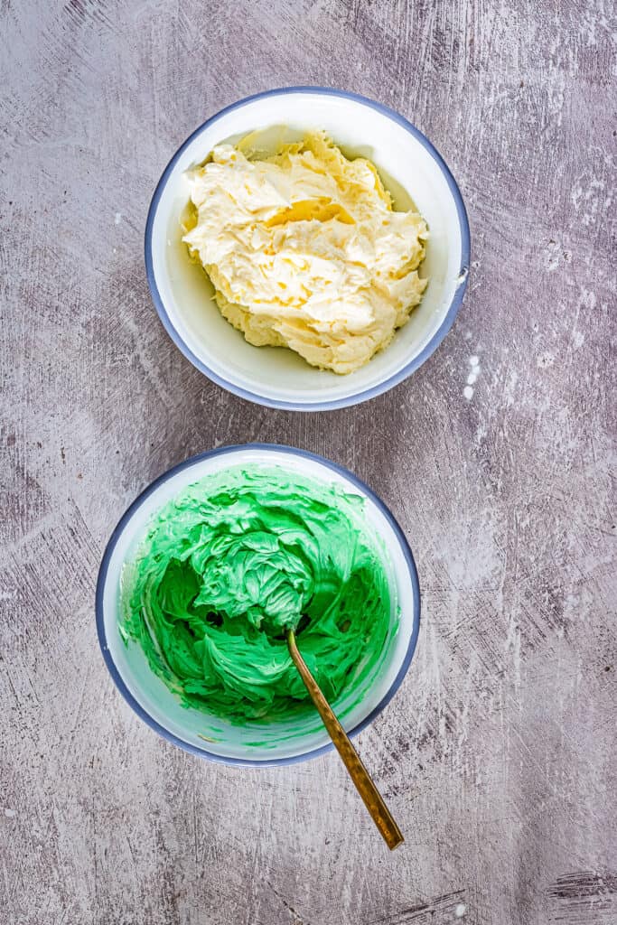 Two bowls of green and vanilla buttercream frosting