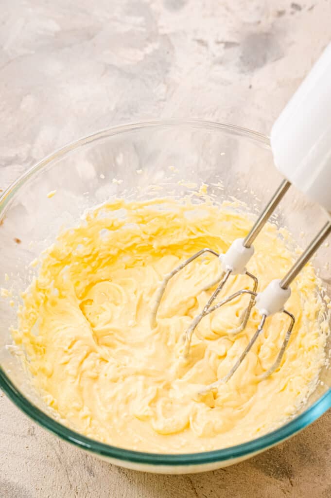 Hand mixer mixing cream cheese for pumpkin muffins