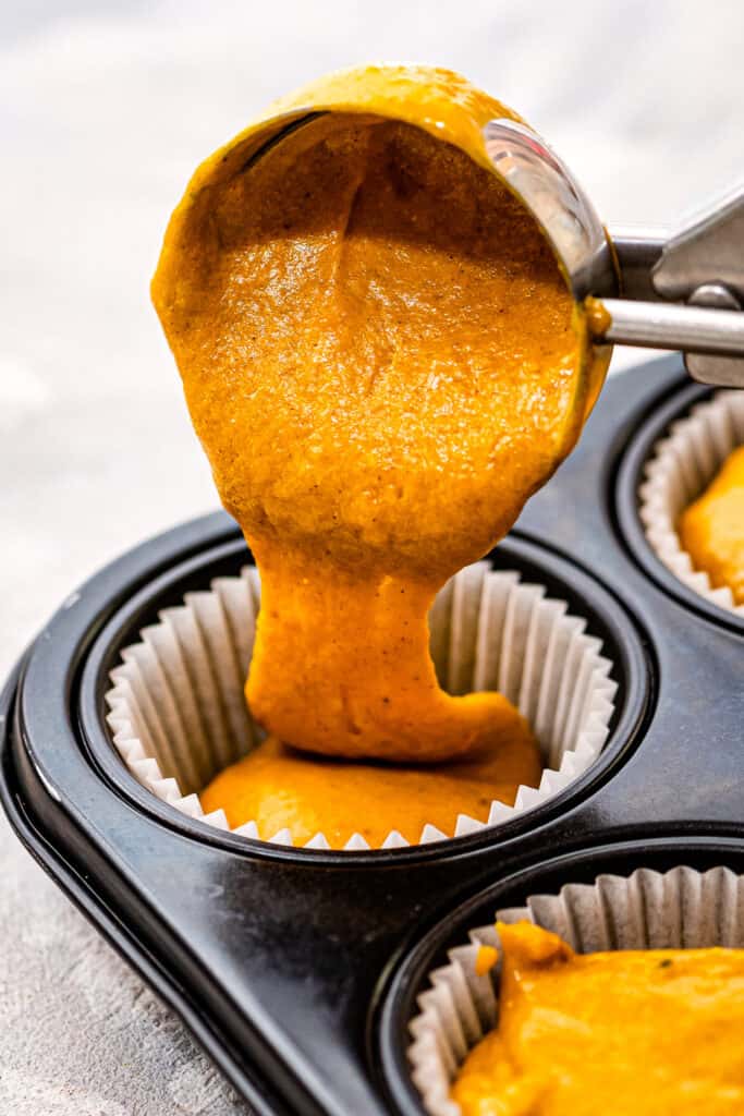 Large cookie scoop putting batter into muffin pan