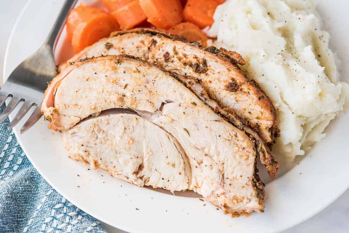 White plate with sliced turkey breast, mashed potatoes and carrots