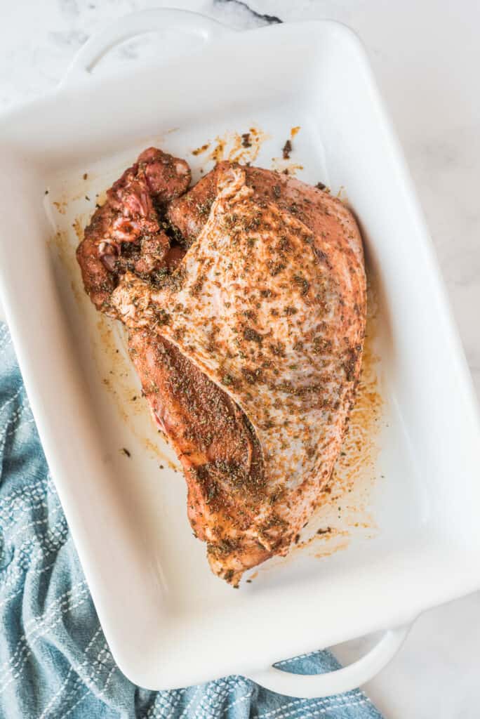 Seasoned turkey breast in white baking dish