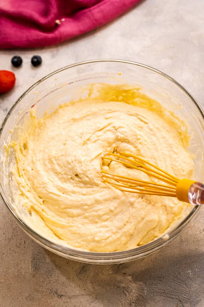 Whisk mixing together pancake batter in glass bowl