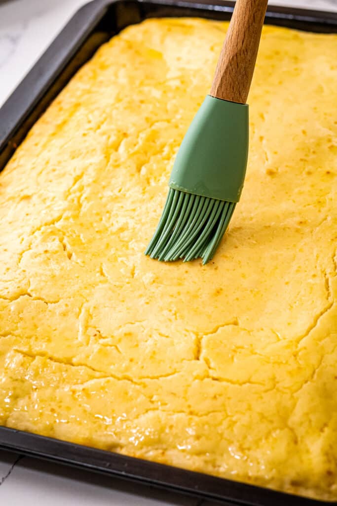 Pastry brush brushing on butter on a pan cake