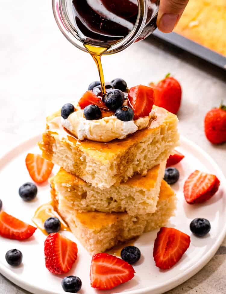 Pouring syrup over a stack of square pancakes