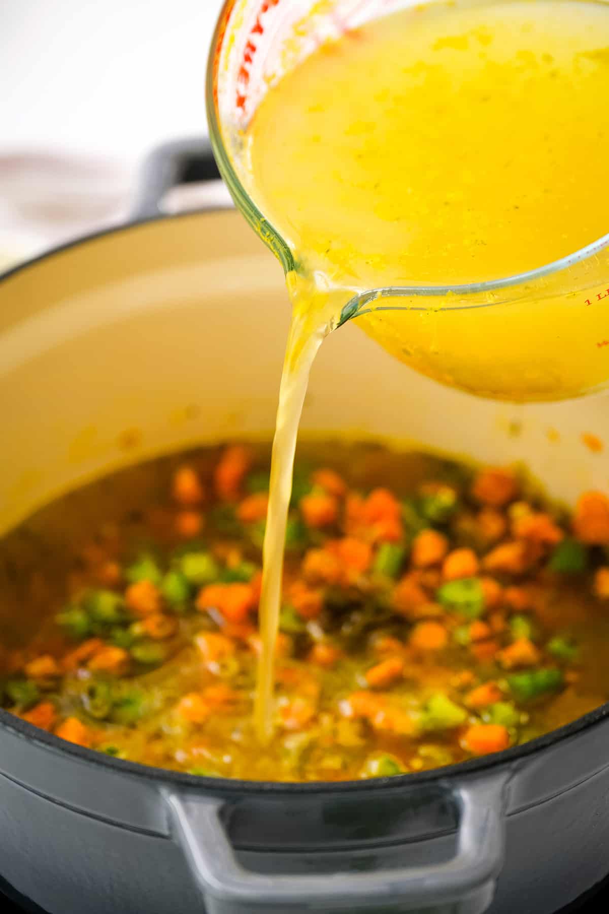 Pouring chicken broth into roux in dutch oven