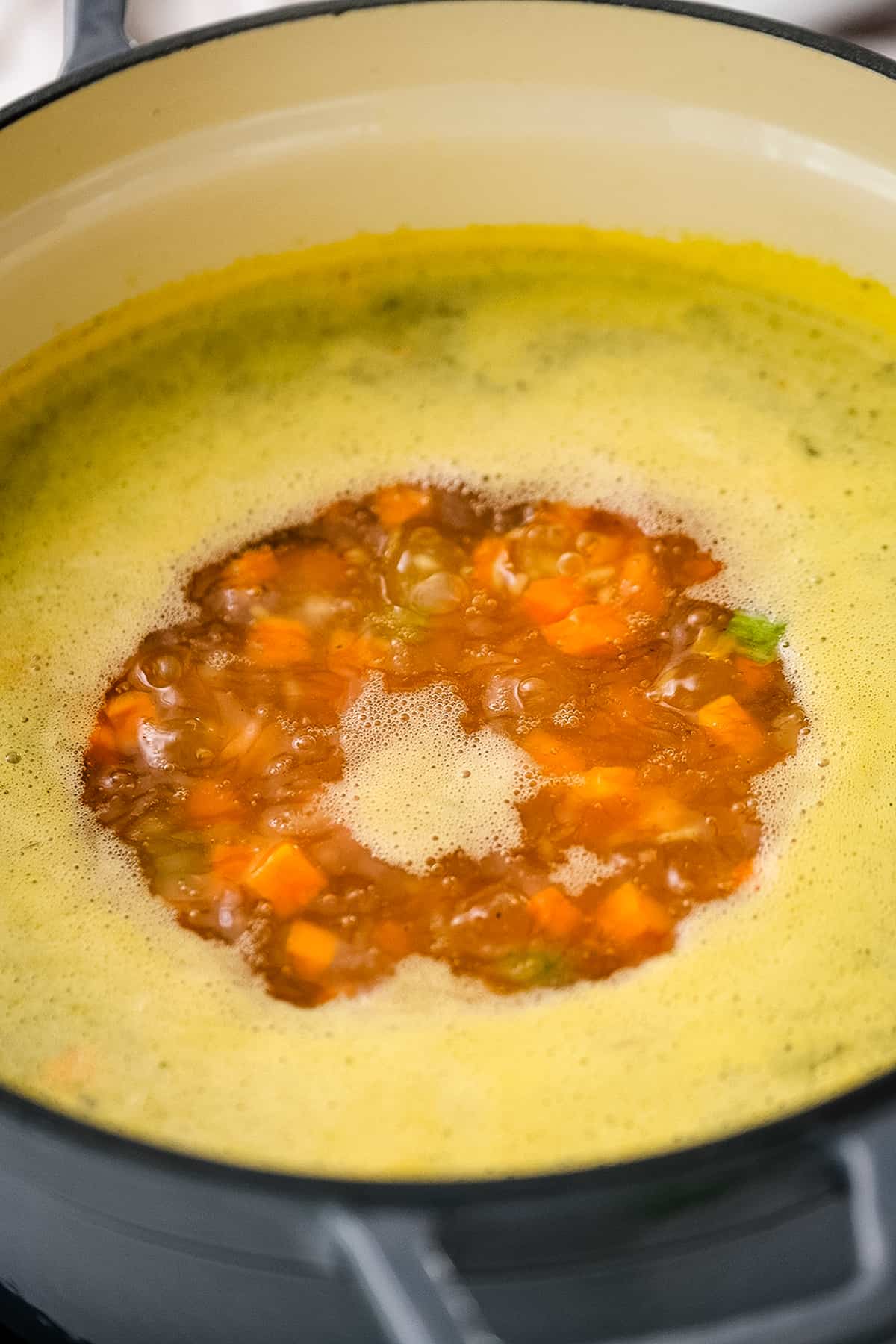 Boiling vegetables in broth for soup in Dutch oven.