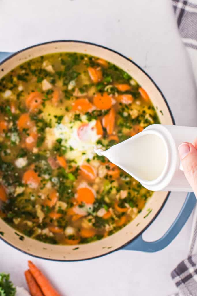 Pouring half and half into white bean soup