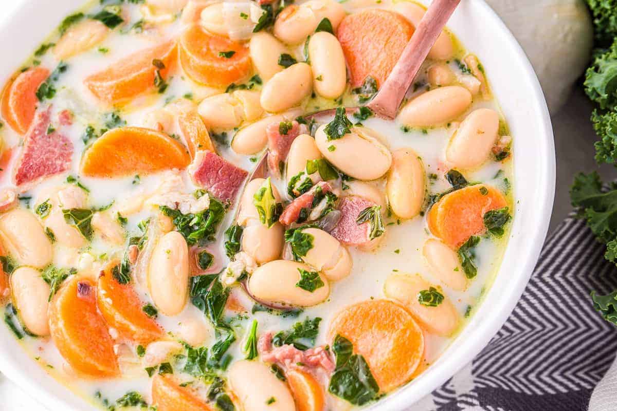 White bowl of white bean soup with spoon