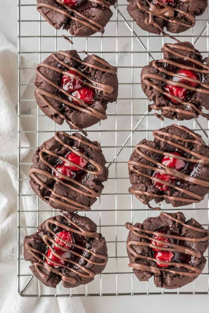 Cooling rack with chocolate cherry thumbprint cookies drizzled in chocolate