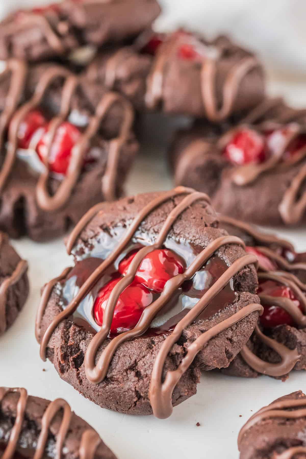 Chocolate Cherry Thumbprint Cookies with chocolate drizzle on white background
