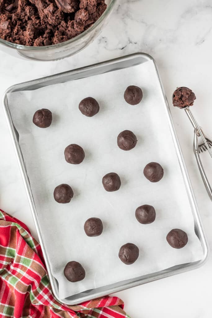 Baking sheet with chocolate cookie dough balls on it