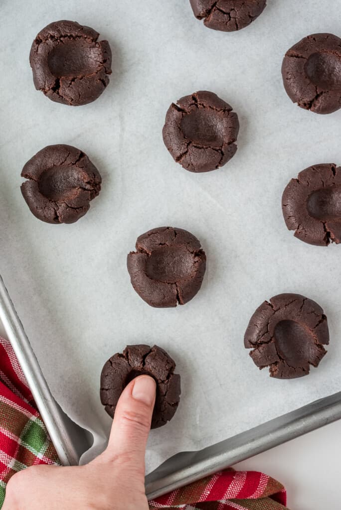 Thumb pushing thumbprint in chocolate cookie dough