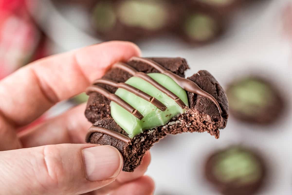 Hand holding a Chocolate Mint Thumbprint Cookie with bite taken out of it