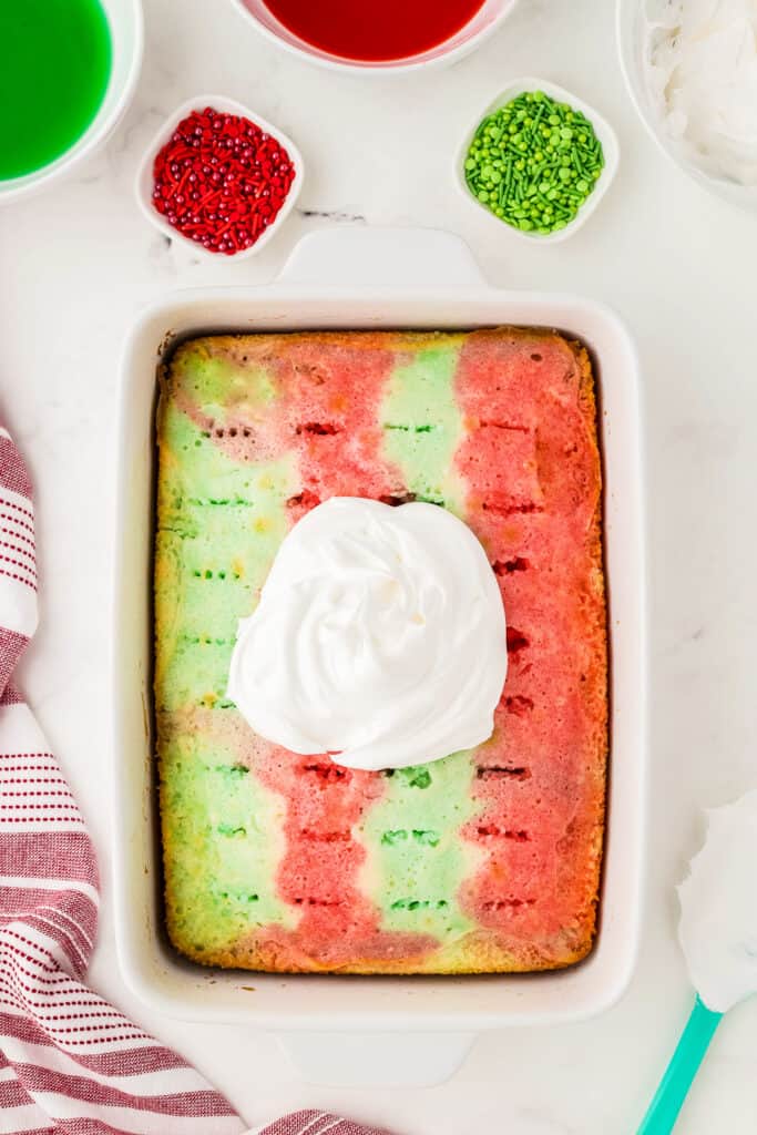 Overhead image of poke cake with a scoop of whipped topping before spreading