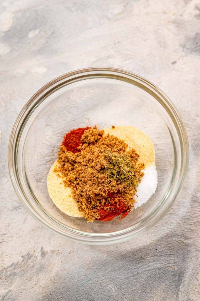 A glass bowl with seasonings for chicken wings