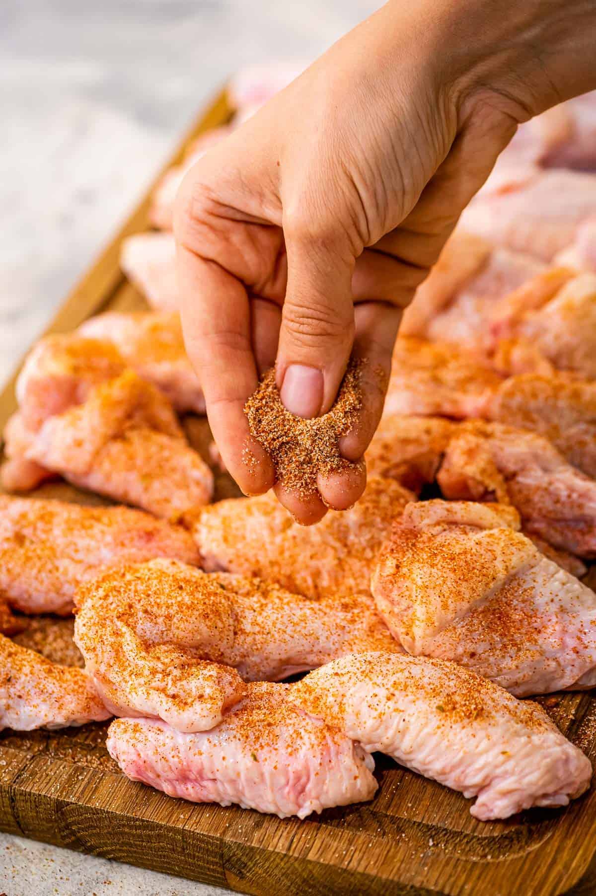 Hand Sprinkling seasoning on chicken wings