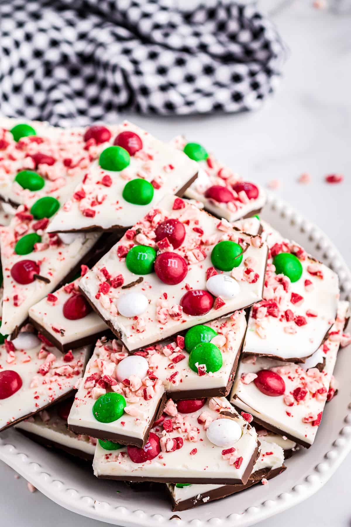 Pieces of peppermint bark on plate with navy check napkin in background