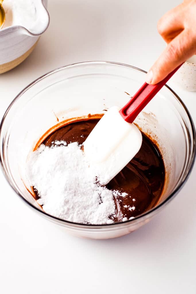 Mixing chocolate glaze for donuts in glass bowl