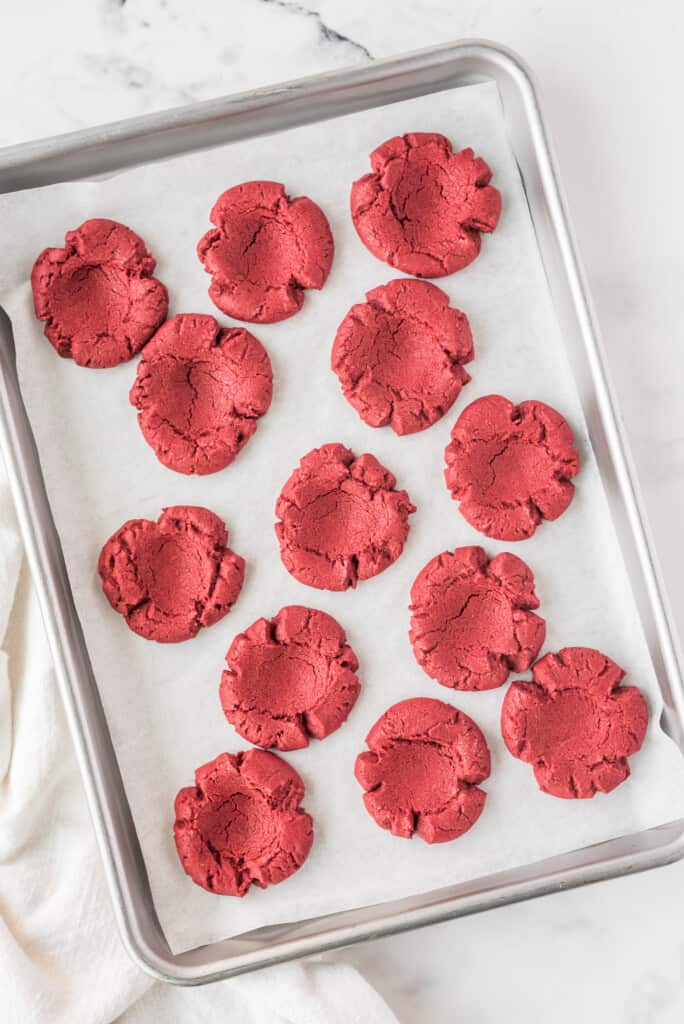 Baked red velvet thumbprint cookies on sheet pan