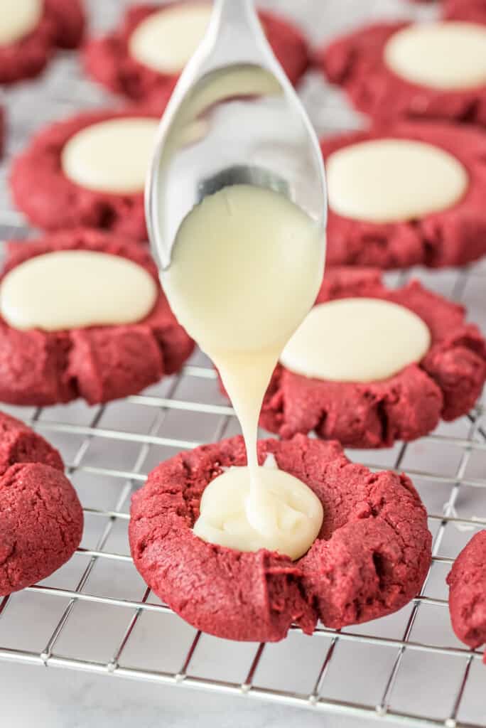 Spooning white chocolate fudge into thumbprint cookie