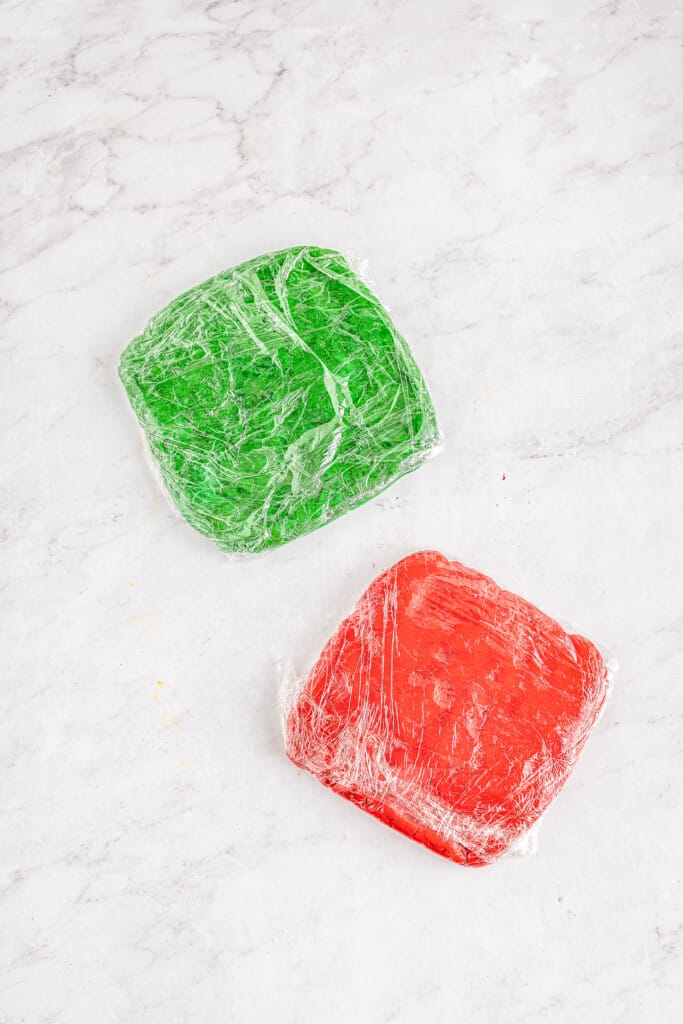 Red and green cookie dough wrapped in plastic wrap