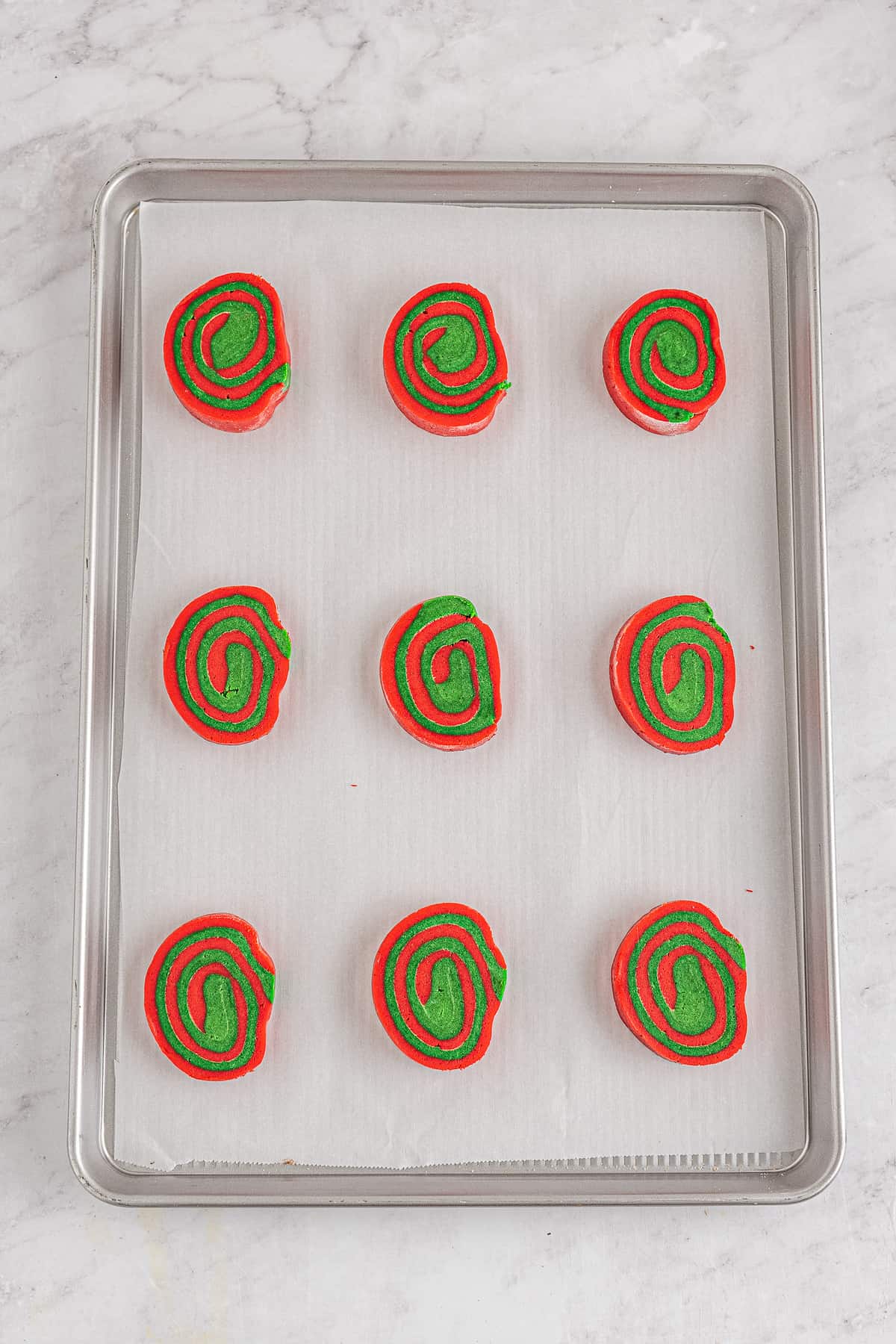 Christmas pinwheel cookies sliced and on baking sheet