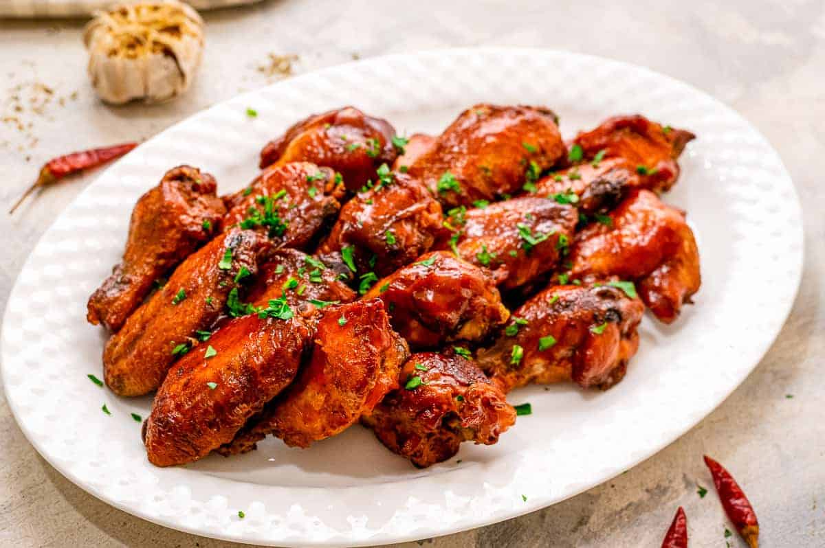 White plate with cooked BBQ chicken wings on them