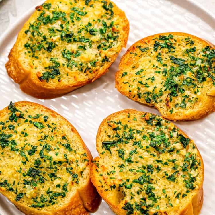 White plate with four pieces of garlic bread on it