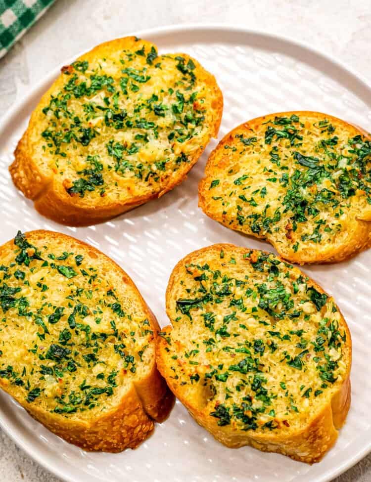 White plate with four pieces of garlic bread on it