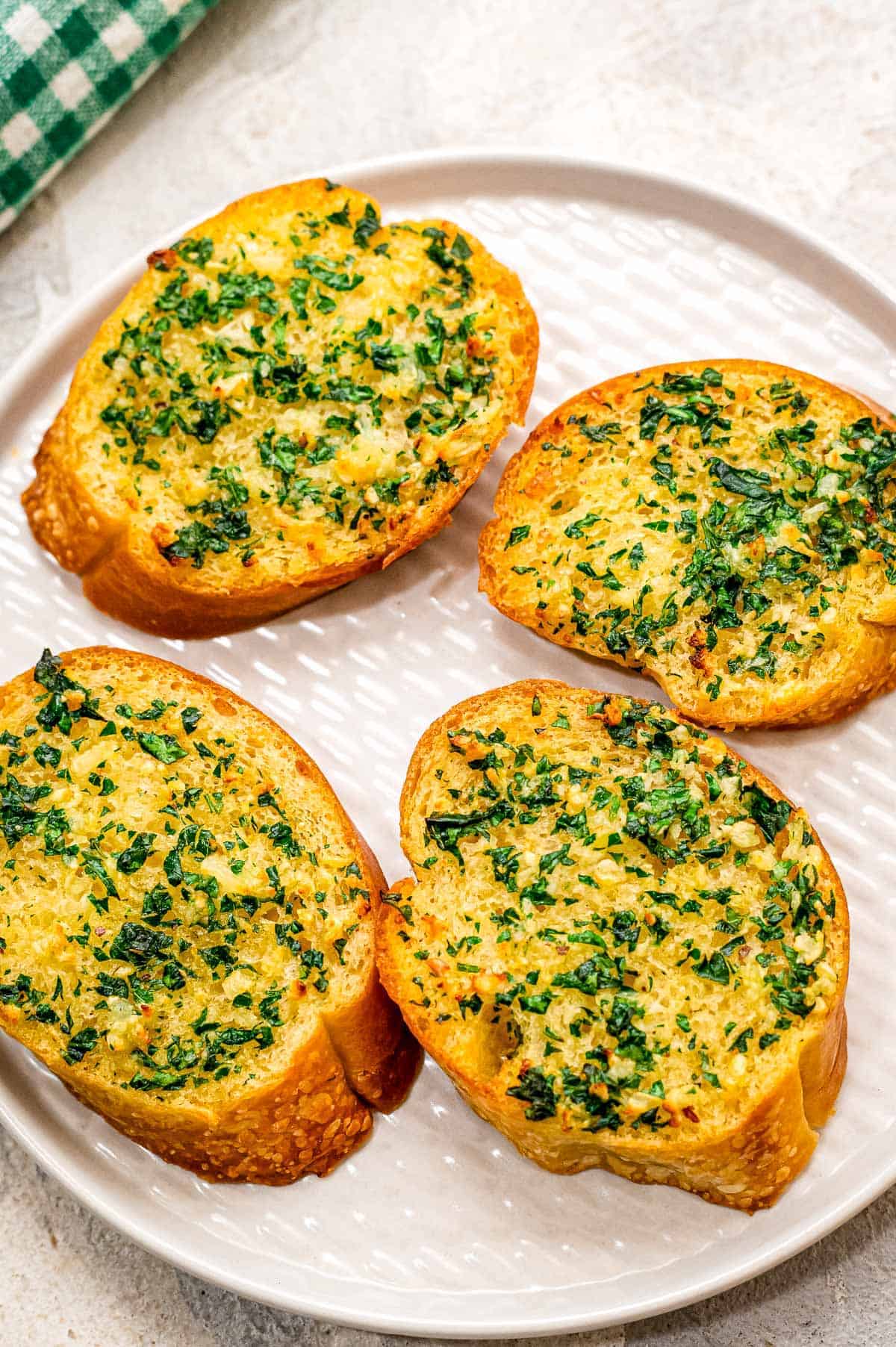 White plate with four pieces of garlic bread on it