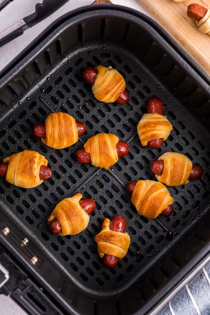 Air Fryer basket with cooked mini air fryer pigs in a blanket