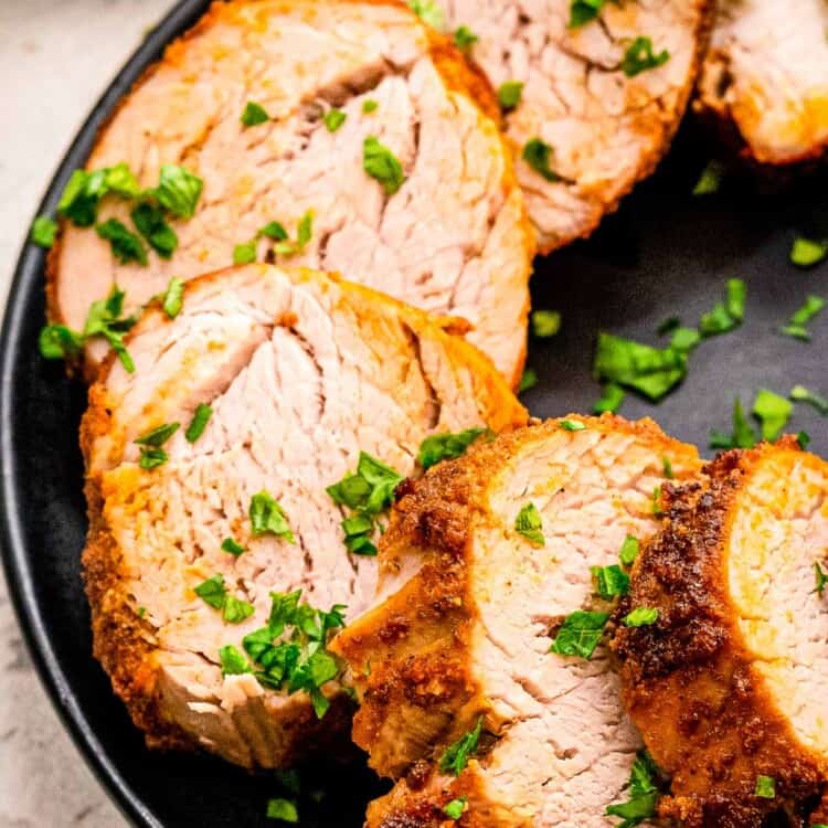 Sliced pork tenderloin on black plate