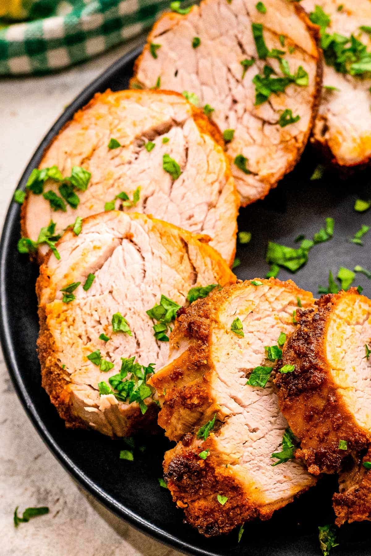 Sliced pork tenderloin on black plate