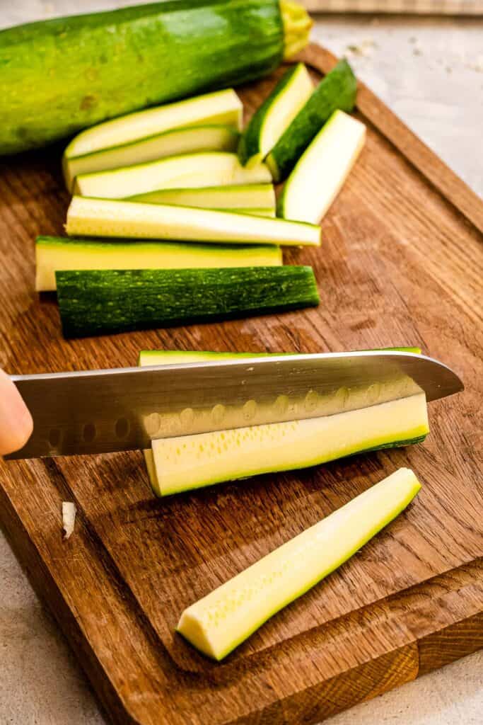 Knife slicing zucchini into fries