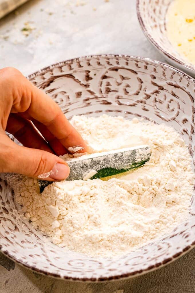 Hand coating a zucchini fry with flour