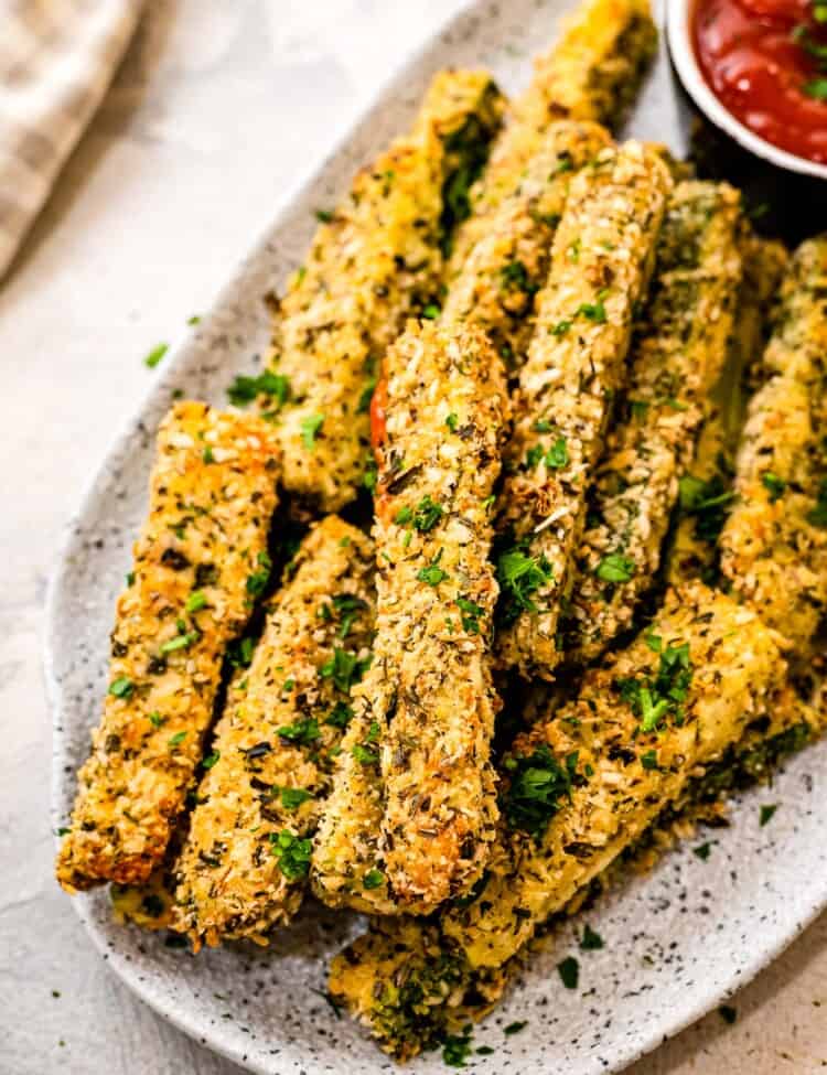 Plate with baked zucchini fries on it and a dish of ketchup