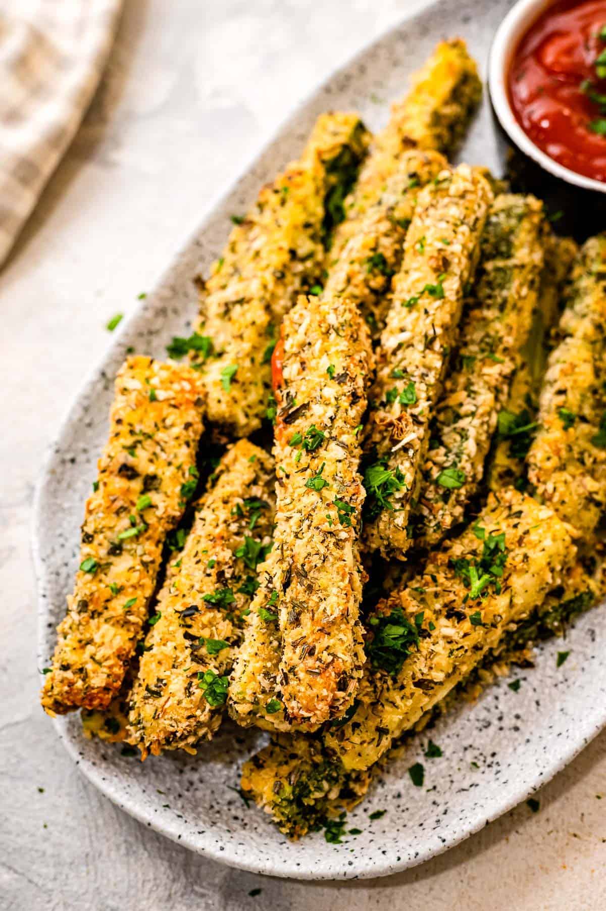 Plate with baked zucchini fries on it and a dish of ketchup