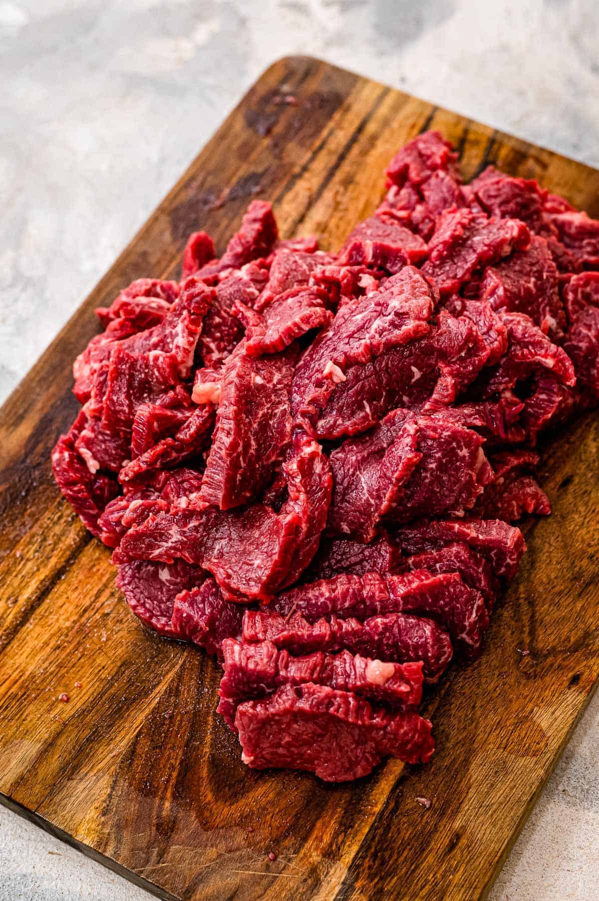 Wooden cutting board with thinly sliced flank steak
