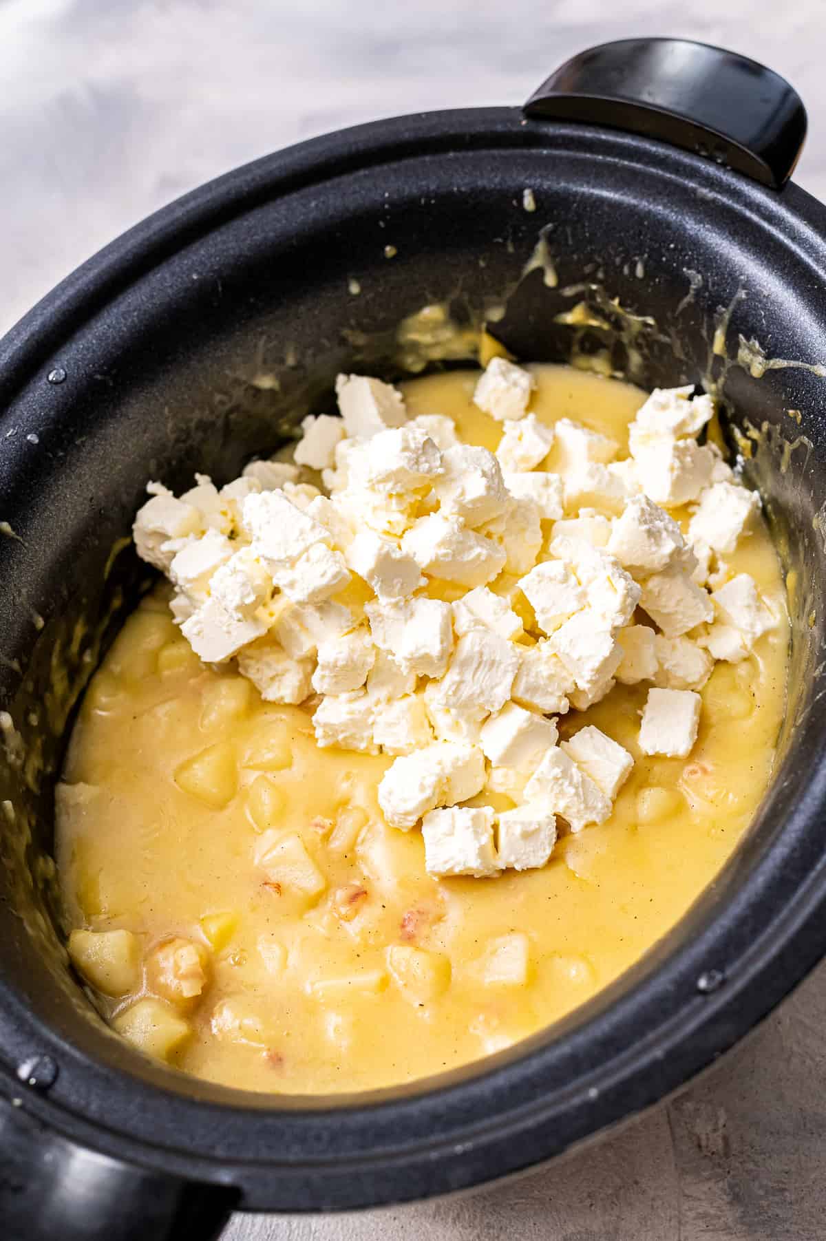 Adding cream cheese to crock pot with soup
