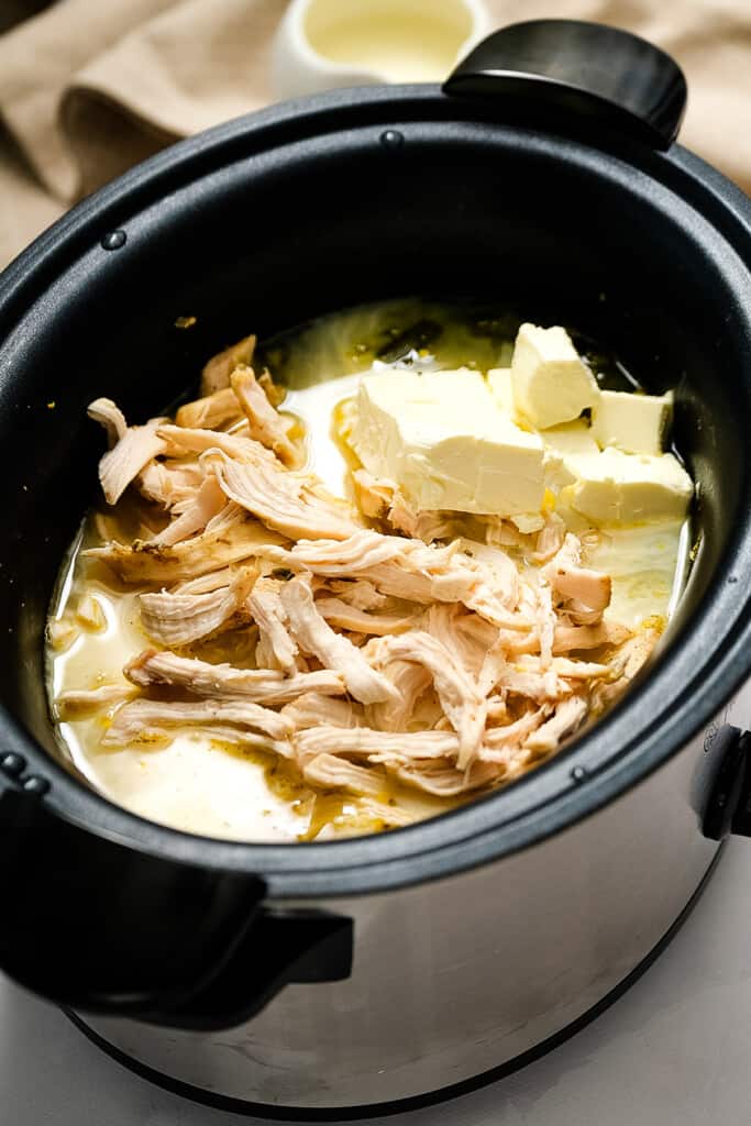 Shredded chicken and cream cheese in black crock pot