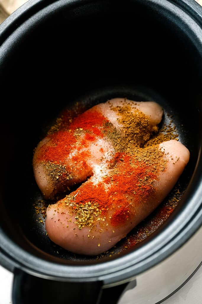 Chicken breasts with seasonings and spices in black crock pot liner